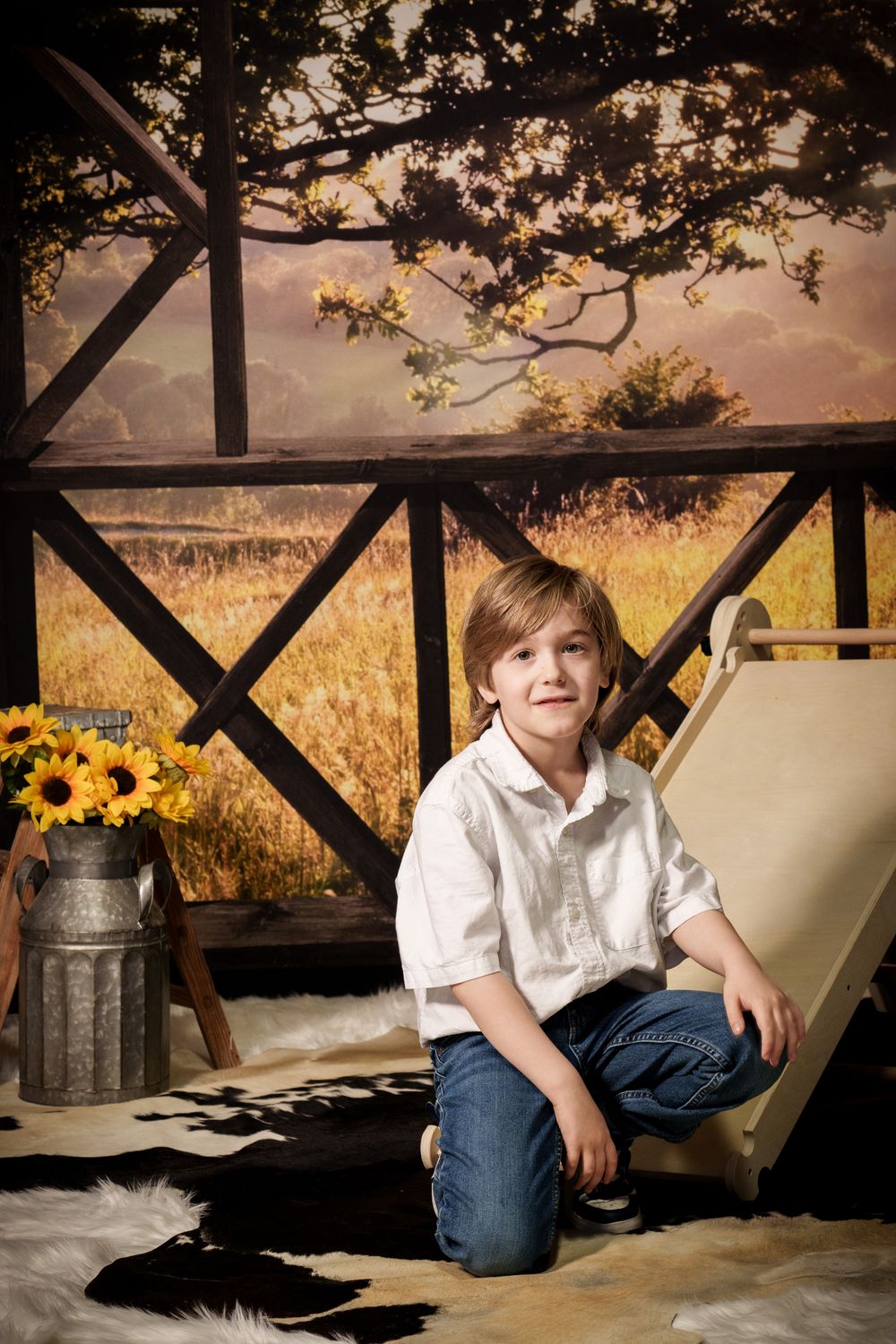 Country studio portrait with rustic wooden fence, sunflowers in milk can, and cowhide rug during golden sunset.