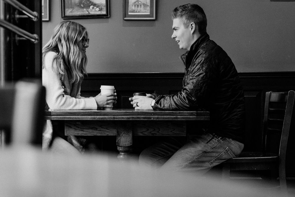 Black and white image of a couple sharing coffee at a cafe table.