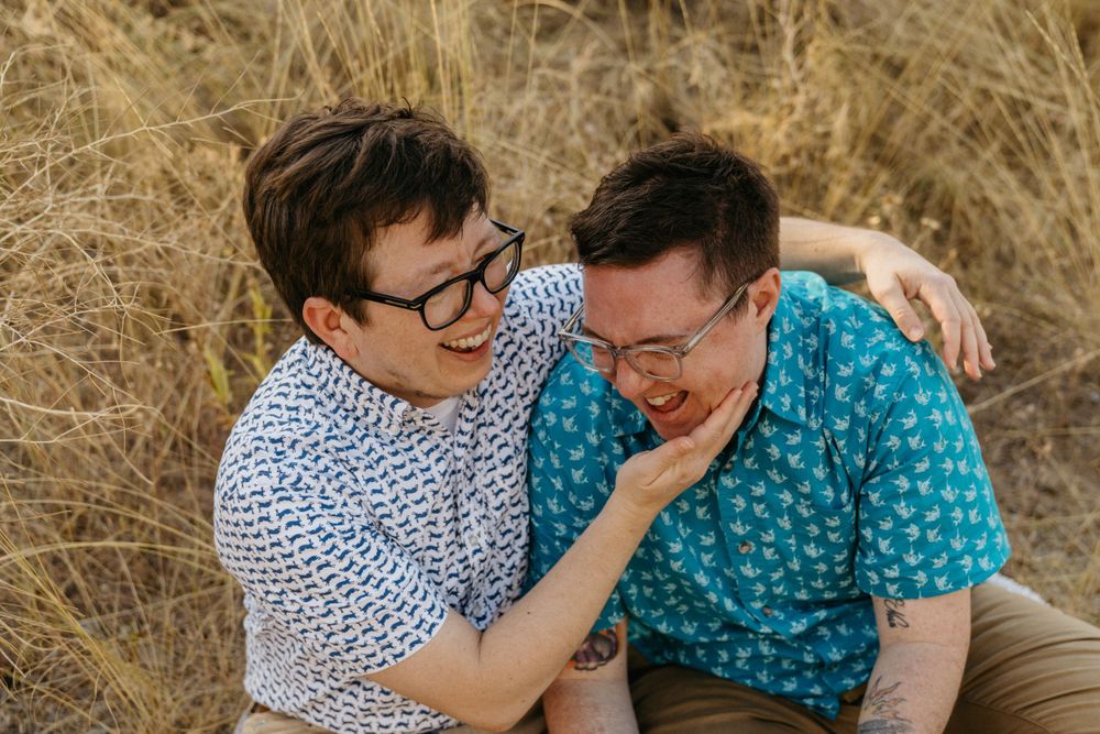 Two people sharing a playful intimate moment in a field of tall grass.