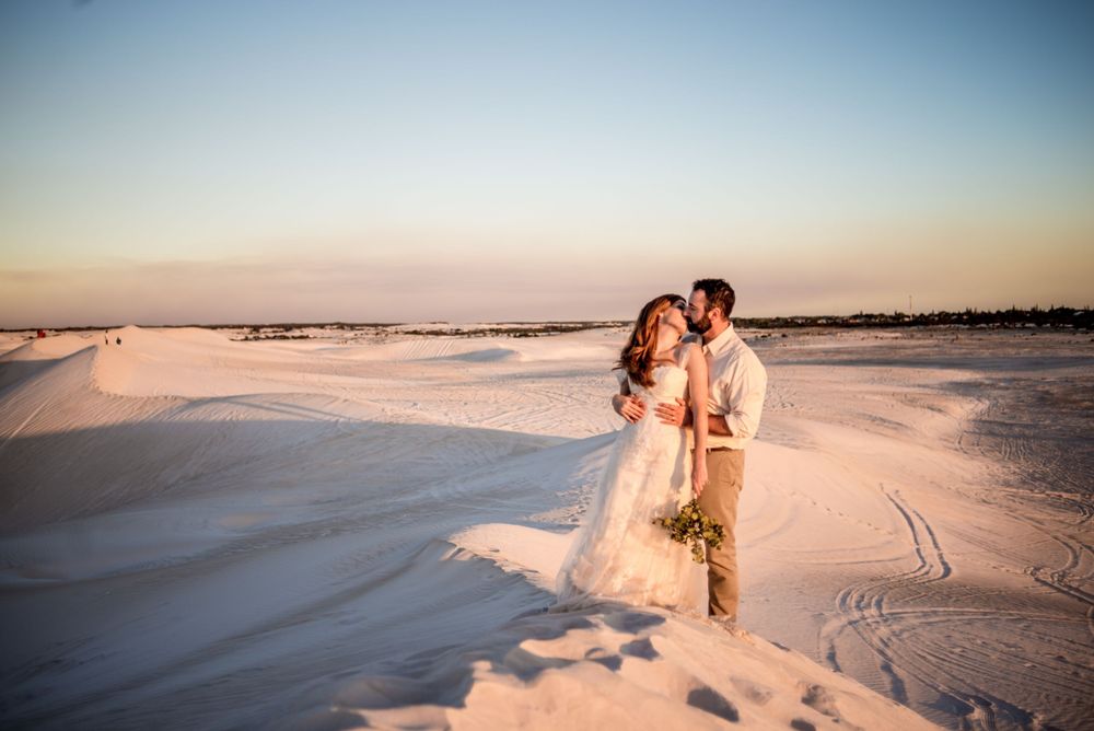 A romantic sunset moment captured on pristine white sand dunes on a beach.