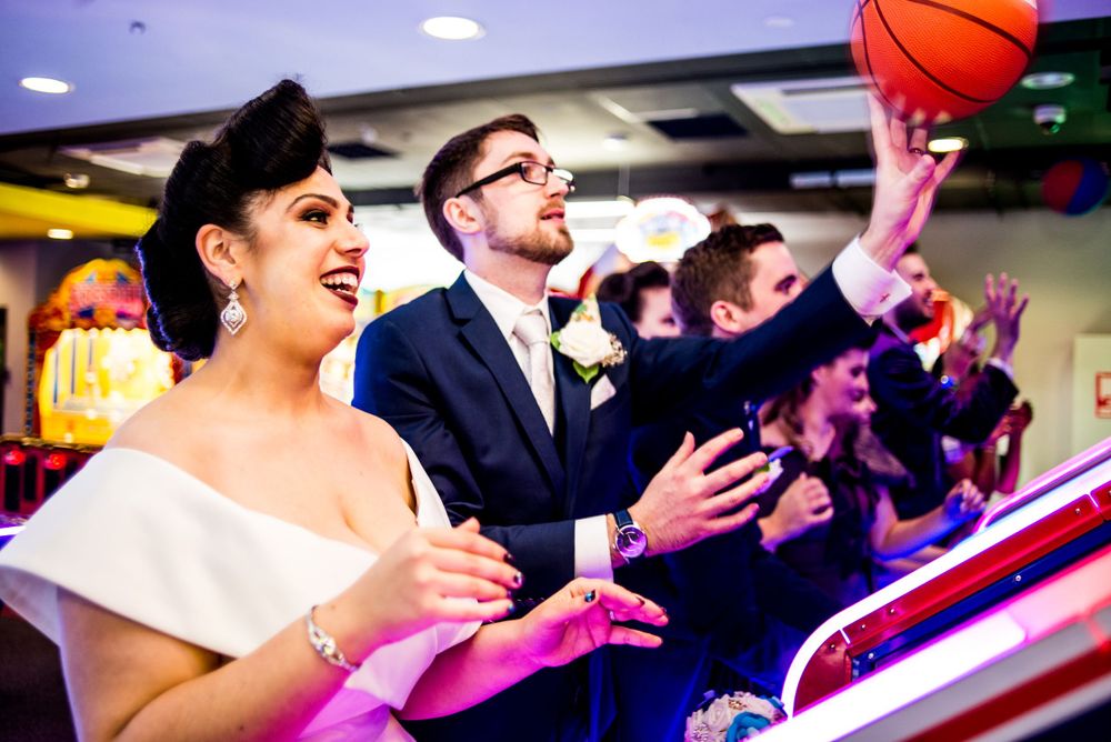 Joyful wedding celebration moment at an arcade with bright colorful lighting. Jasper Brewing Company, Jasper Fitness & Aquatic Centre, Jaspe