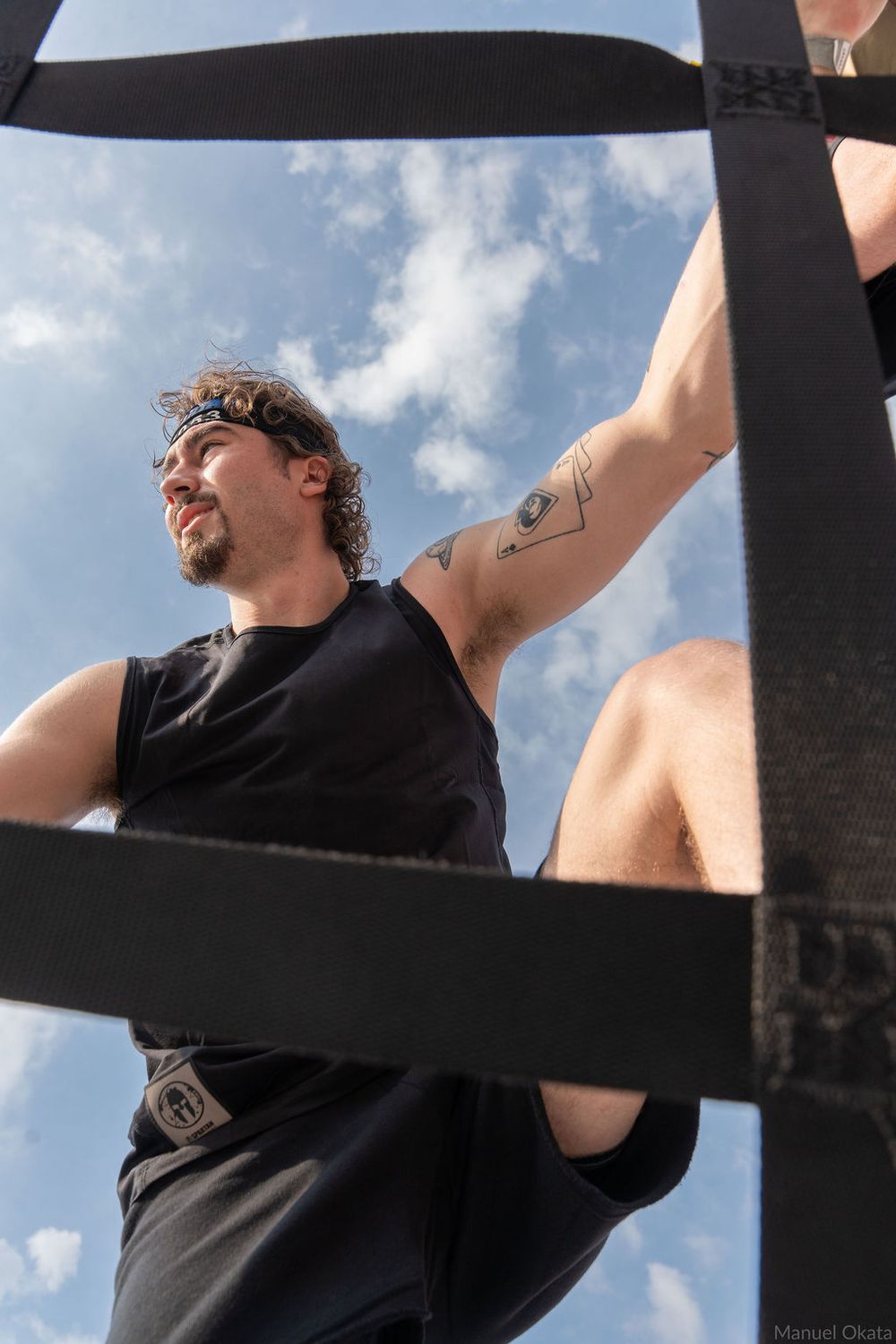 Two Spartan athletes climbing a cargo net obstacle during stadium race, capturing teamwork, strength, and determination.