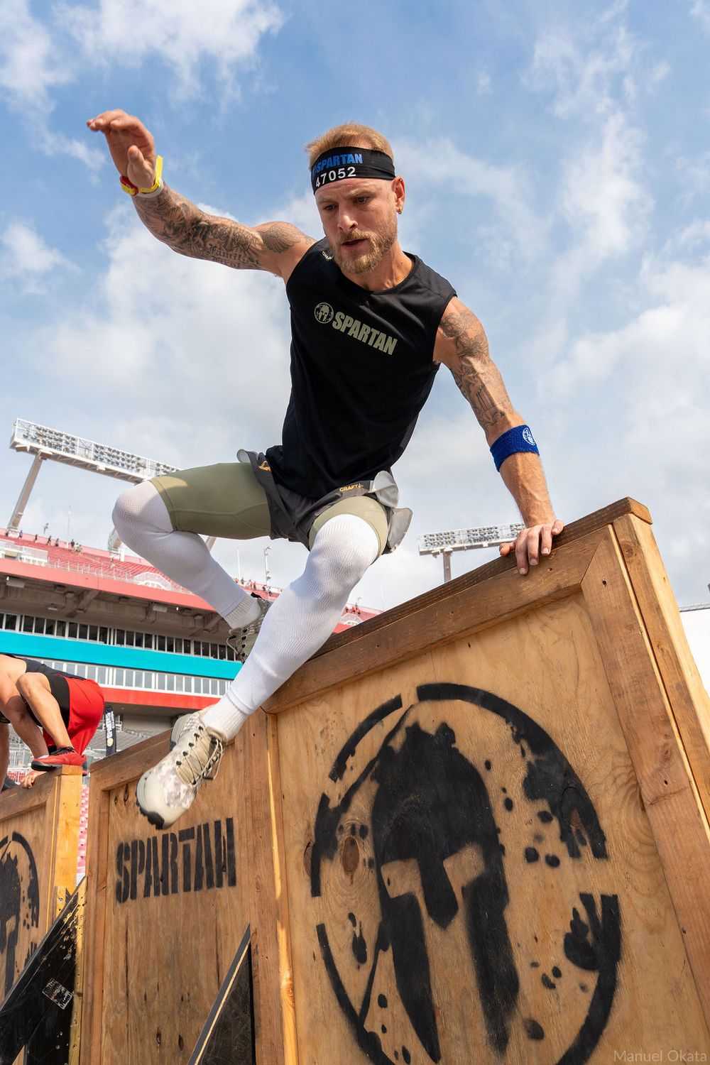 Athlete clearing a Spartan Race obstacle during a commercial sports photography session capturing action, strength, and determination