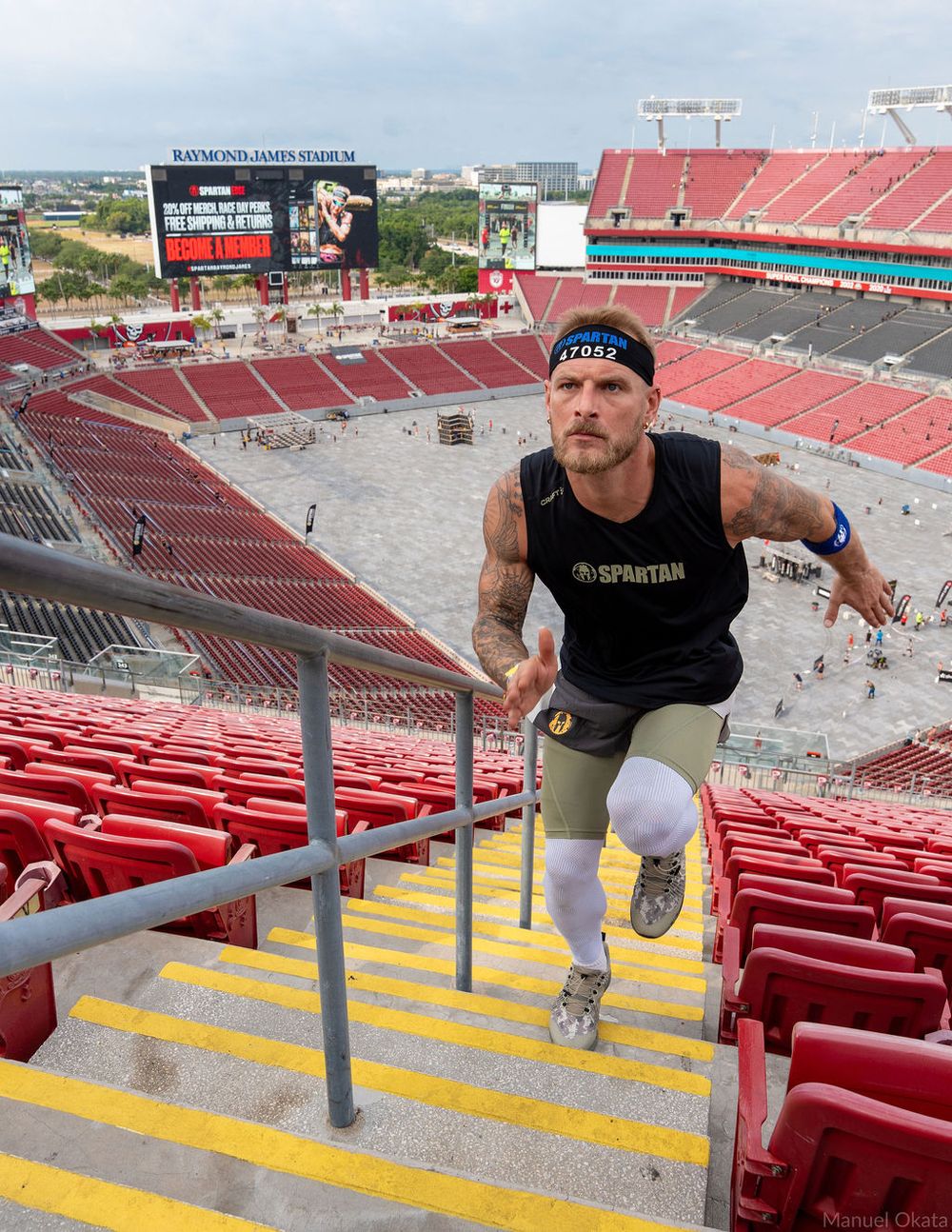 Athlete sprinting up stadium stairs during Spartan Race training, showcasing strength, endurance, and commercial sports photography.