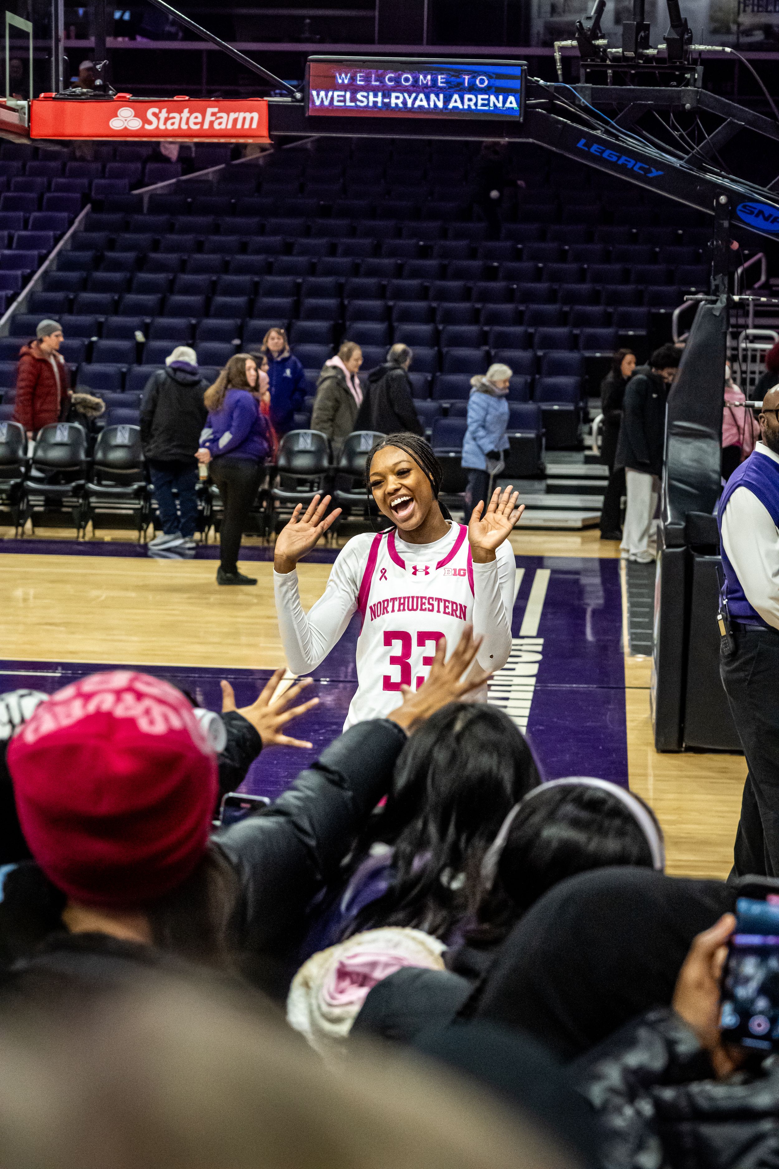 A basketball player in jersey number 33 waves enthusiastically to fans at Welsh-Ryan Arena.