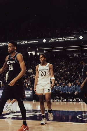 Basketball players in black and white uniforms compete during a professional game on an indoor court.
