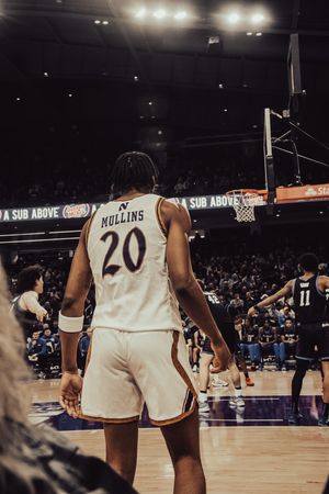 Basketball player wearing jersey number 20 stands on court during indoor game under arena lighting.