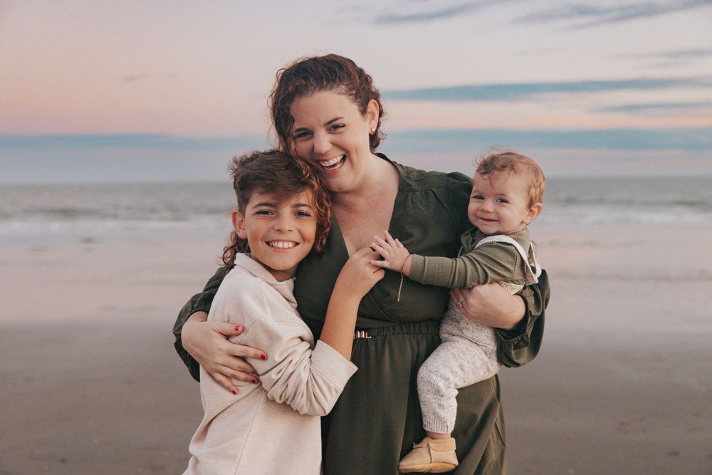 A family enjoys tender moments together while walking along a peaceful beach at sunset.