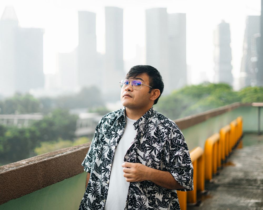 A casual portrait on a rooftop with foggy skyscrapers in the background.