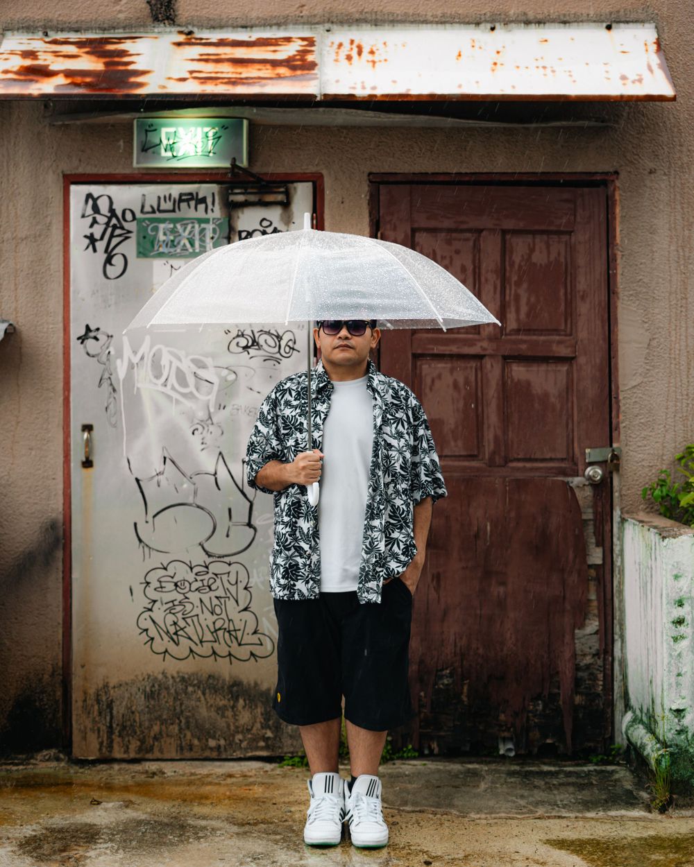 Urban fashion portrait with clear umbrella against weathered door with graffiti background.