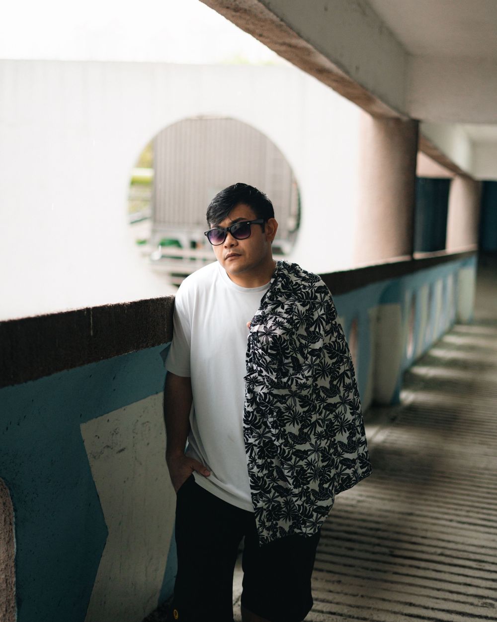 Urban fashion portrait in covered walkway with black and white patterned shirt.