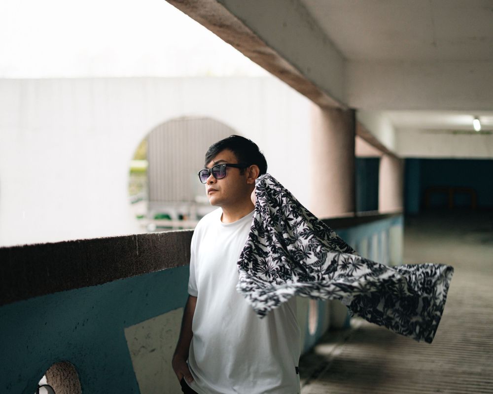 Creative fashion photo with flowing patterned shirt in urban corridor setting.