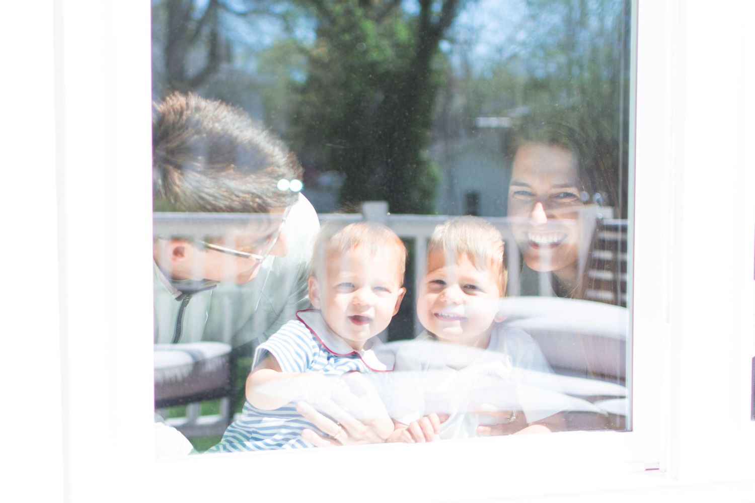 Blurry and faded polaroid style photo showing four people together through window glass or reflection.