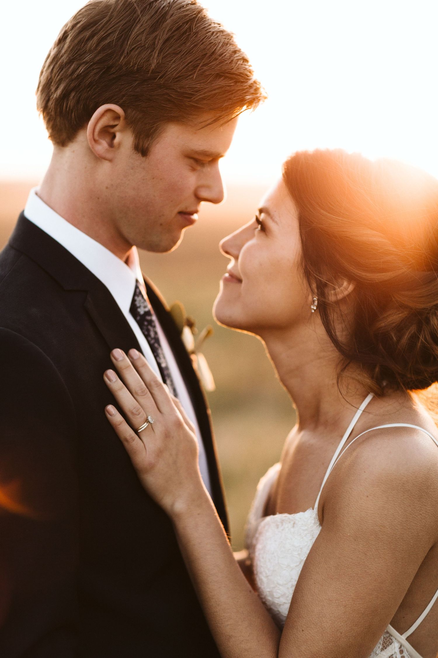 Bride and Groom smiling in a field at sunset