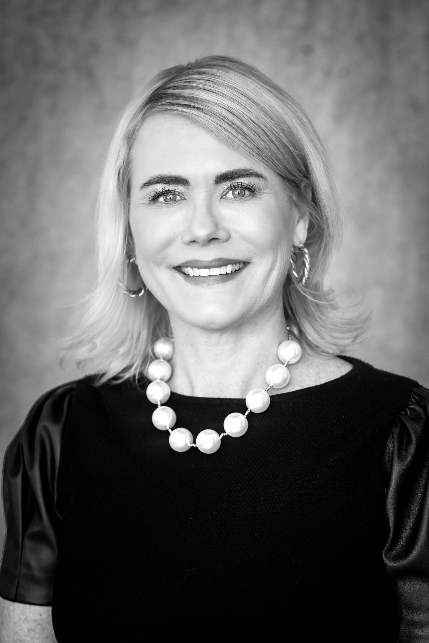 Black and white headshot of a woman against a gray backdrop taken by Milwaukee headshot and branding photographer Rachel Dickman.
