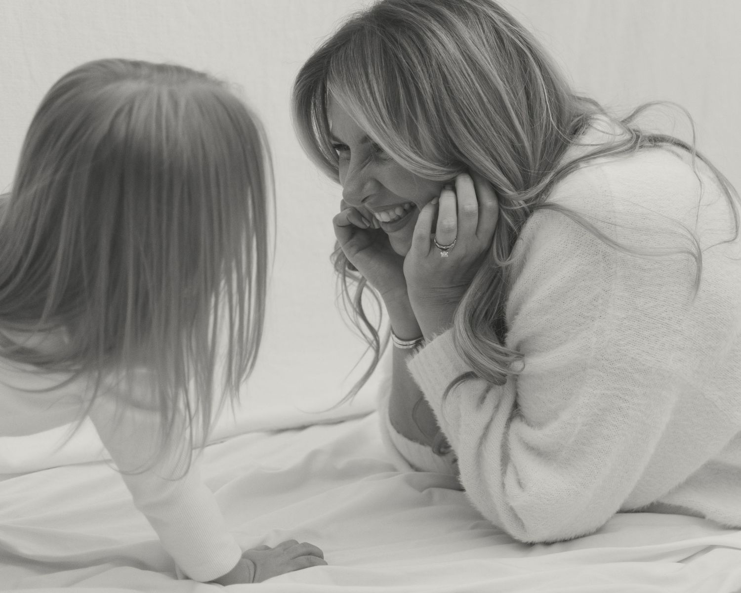 A candid black and white portrait captures a sweet moment between a mom and child playing together.