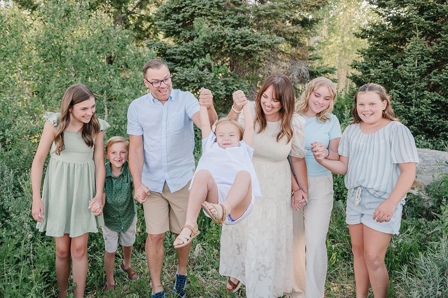 Group gathered together outdoors in a natural setting with lush green foliage in the background.