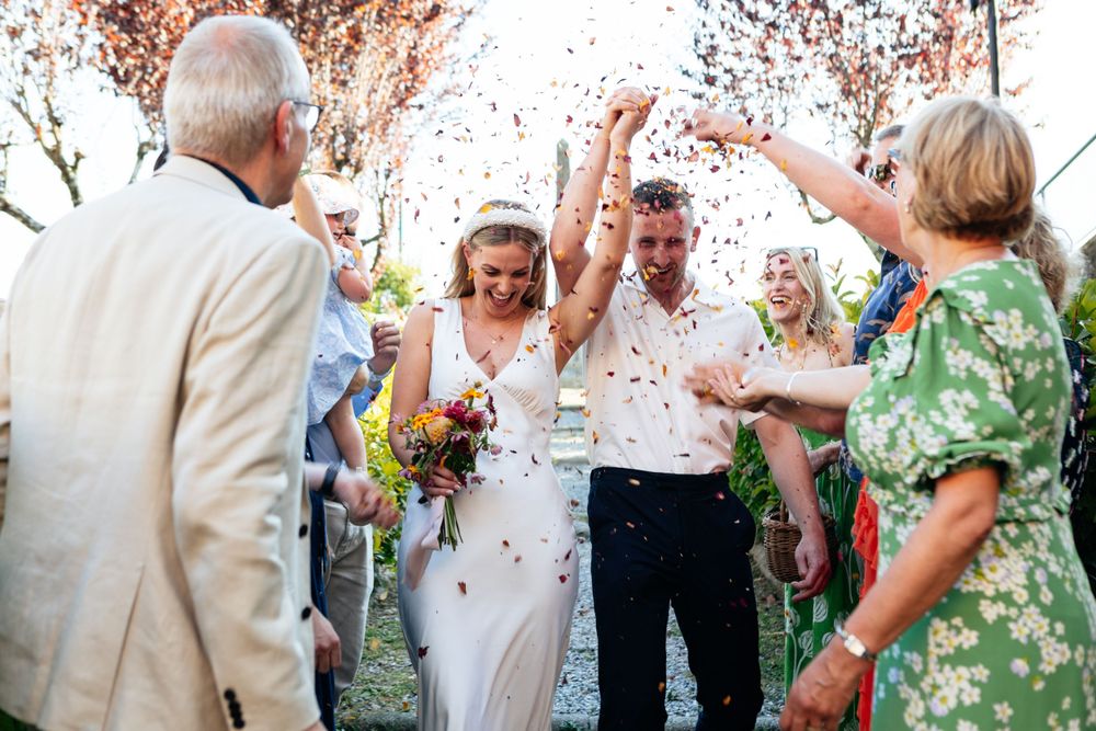 Celebrations at a small intimate wedding in Tuscany as the newly wedded couple are showered with confetti by their close family.