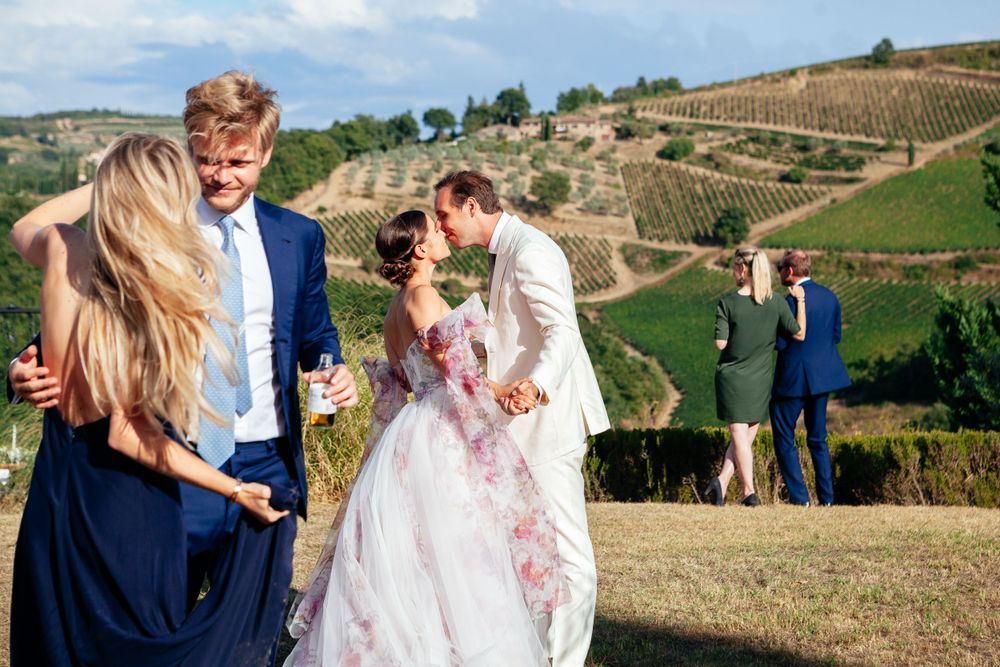 Joyful Italy wedding celebration at scenic vineyard with rolling hills and rows of grapevines in the background.