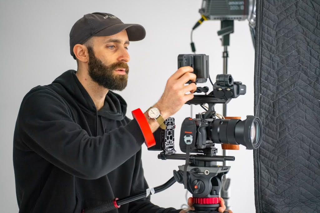Camera operator adjusts professional cinema camera rig with stabilizer during video production shoot.