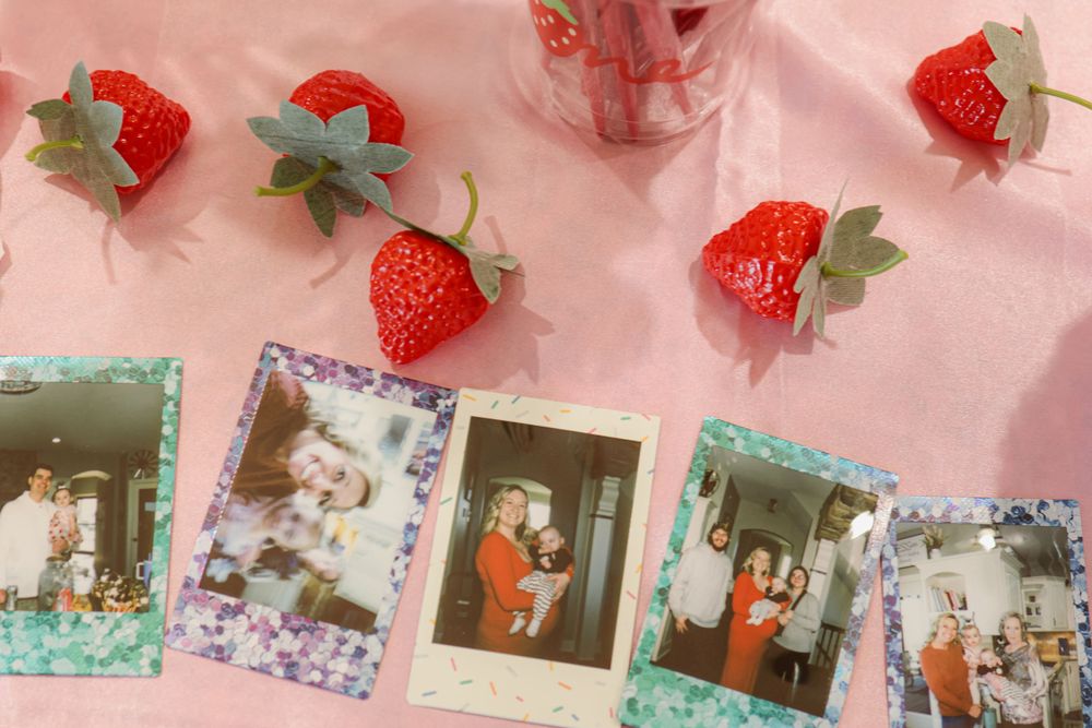 Pink themed party decorations with strawberry accents and vintage photographs.