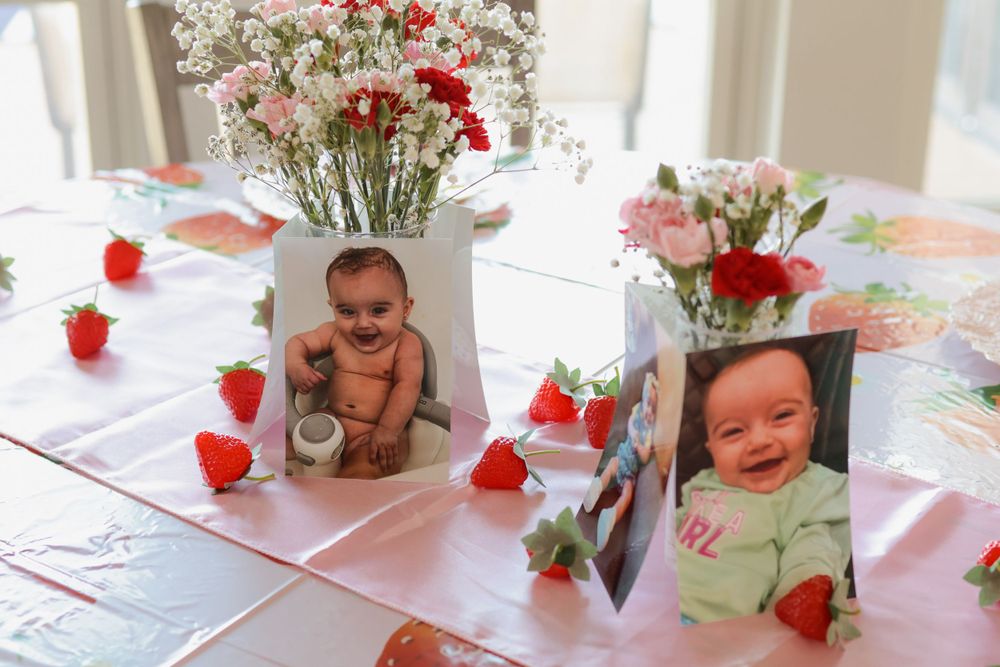 Party setup with red floral arrangements and strawberry themed decorations.