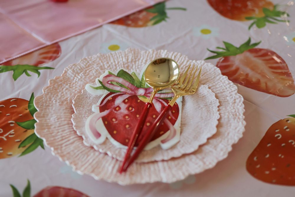 Delicate paper plates decorated with strawberry patterns and pink accents for a party setting.