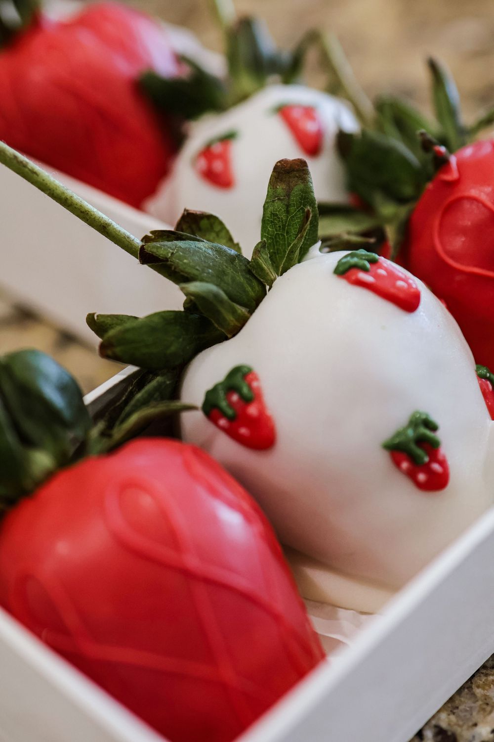 Red strawberry-themed party decorations arranged in white boxes with green leaf accents.
