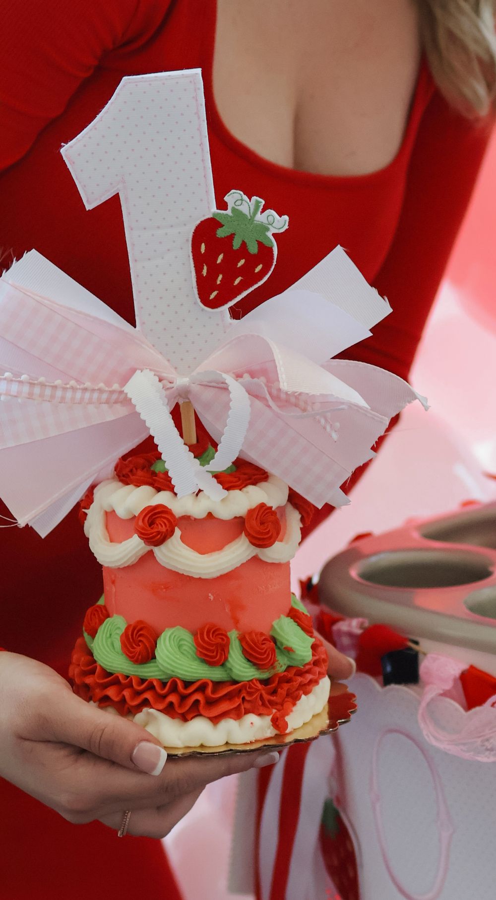 Strawberry themed birthday cake with white and red frosting details being served at a party.