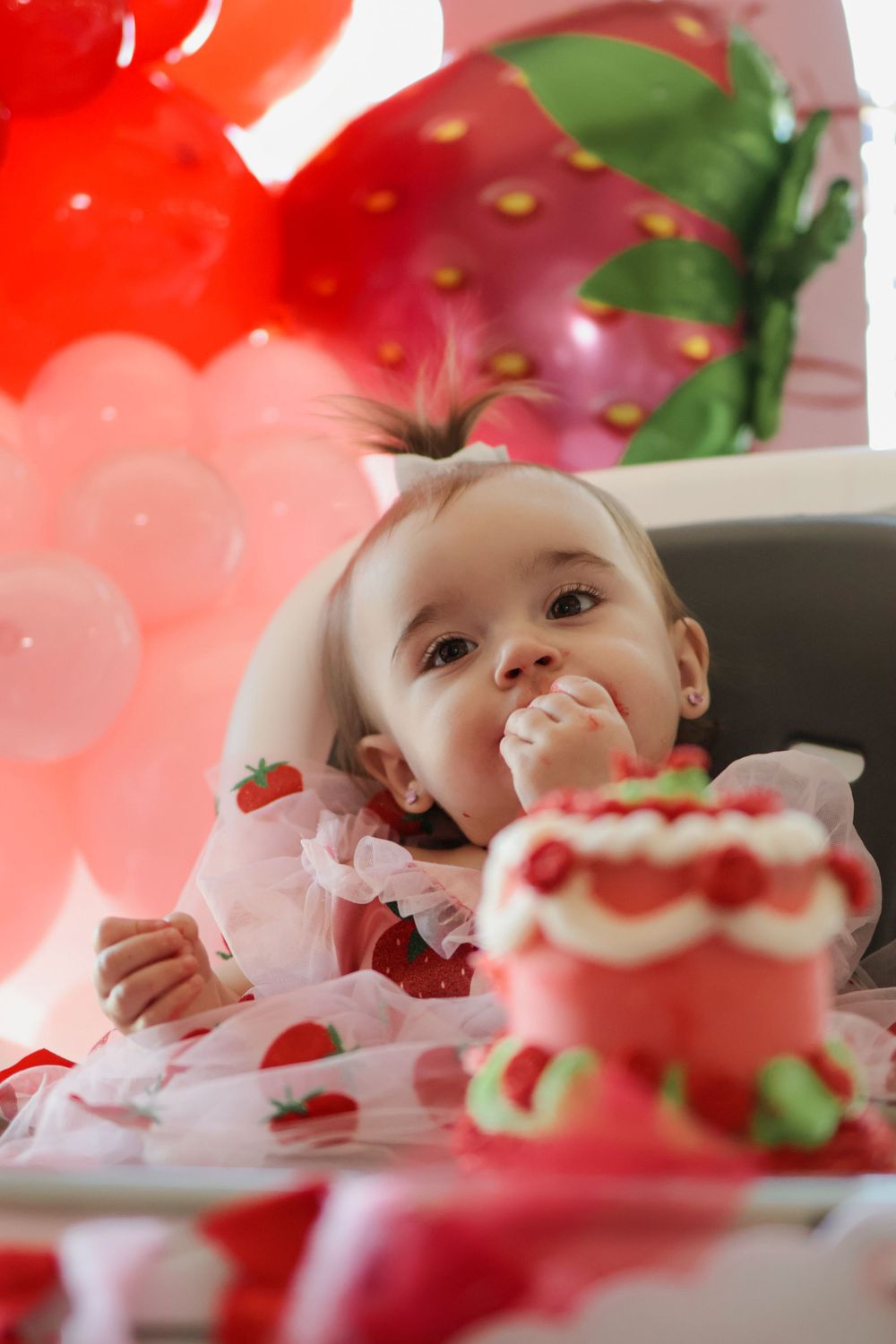 Strawberry themed birthday celebration with cake and pink party decorations.