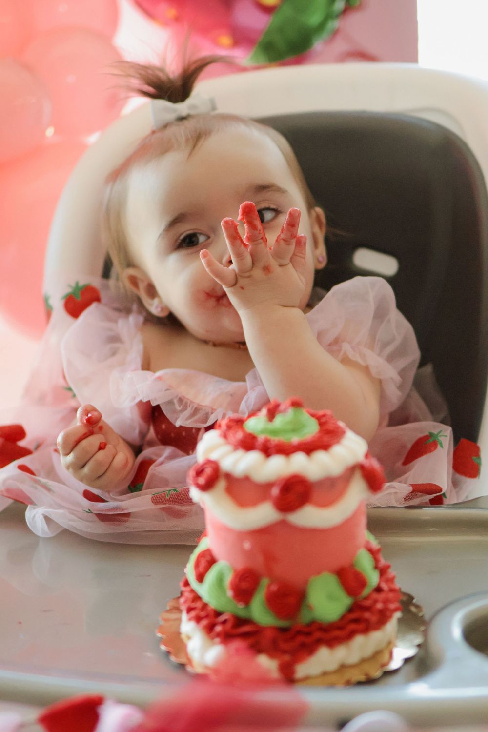First birthday celebration with strawberry themed cake and pink party decorations.