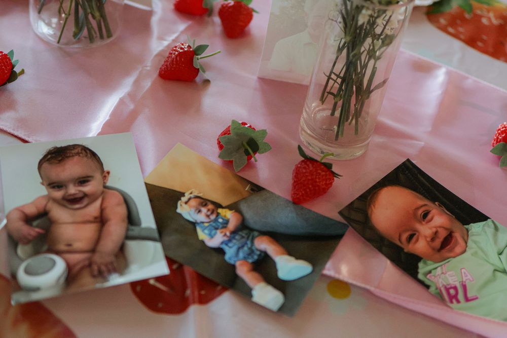 Collection of photographs displayed on a pink surface with strawberry decorations.