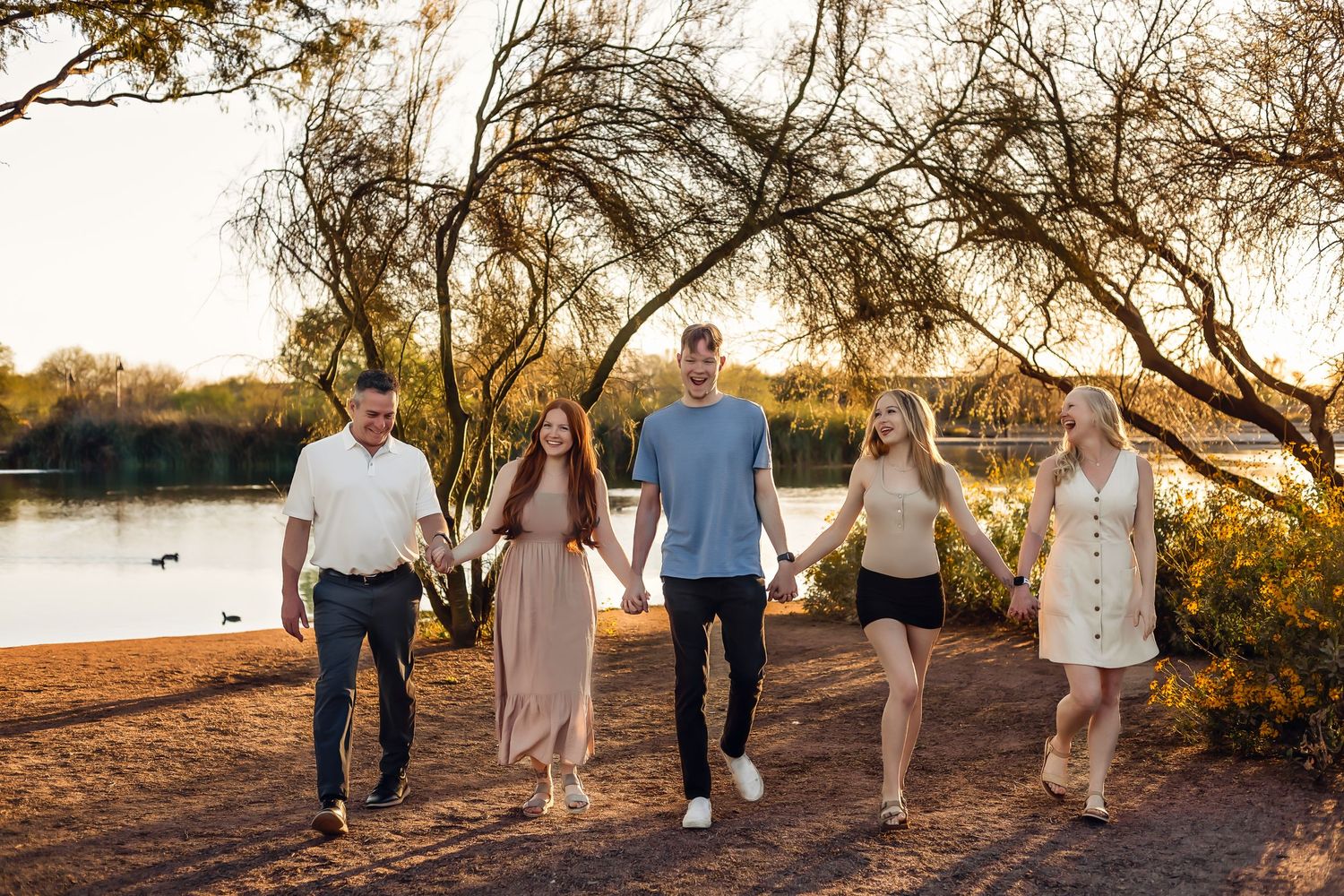 Family group walking together along waterfront path at sunset for Fall photo session in Chandler