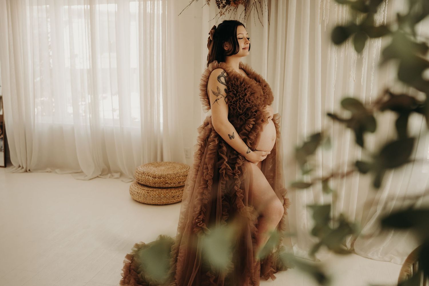 Pregnant woman wearing a flowing dress, embracing her baby bump during a serene maternity photoshoot.