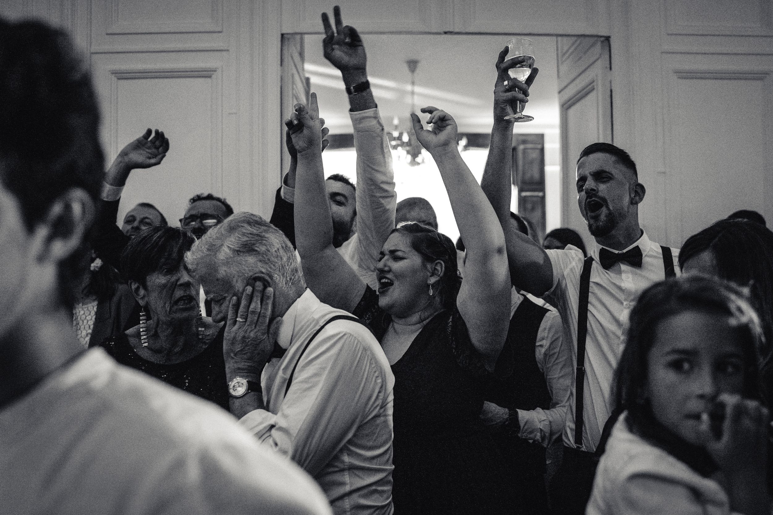 Soirée du mariage dans la salle réception du chateau les invités crient de joie en levant les bras père de la mariée a mal aux oreilles nb