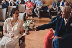 Dans la salle de la mairie du Havre, cérémonie civile, la mariée tend son bouquet à son père assis à côté d'elle, ils se regardent très émus