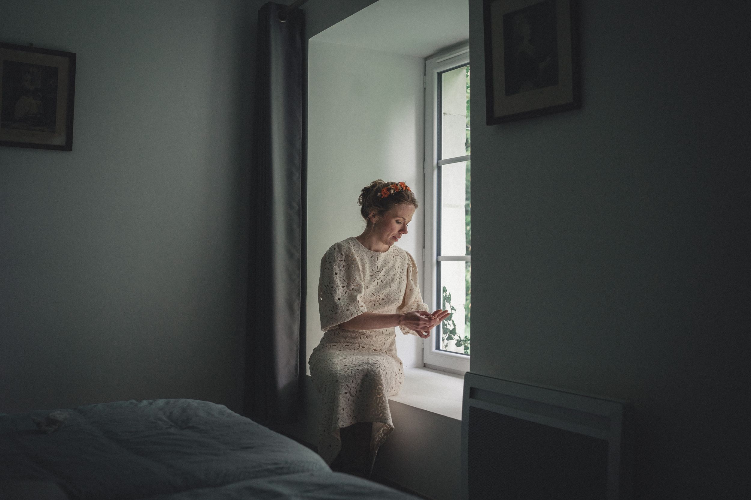 Préparatifs de la mariée couronne de fleurs, assise devant la fenêtre de sa chambre et regarde sa main qui aura bientôt la bague au doigt
