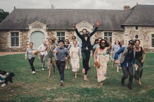 Photo de groupe de mariage, les mariés avec tous leurs témoins et amis alignés courent en sautant et criant de joie dans le parc du chateau