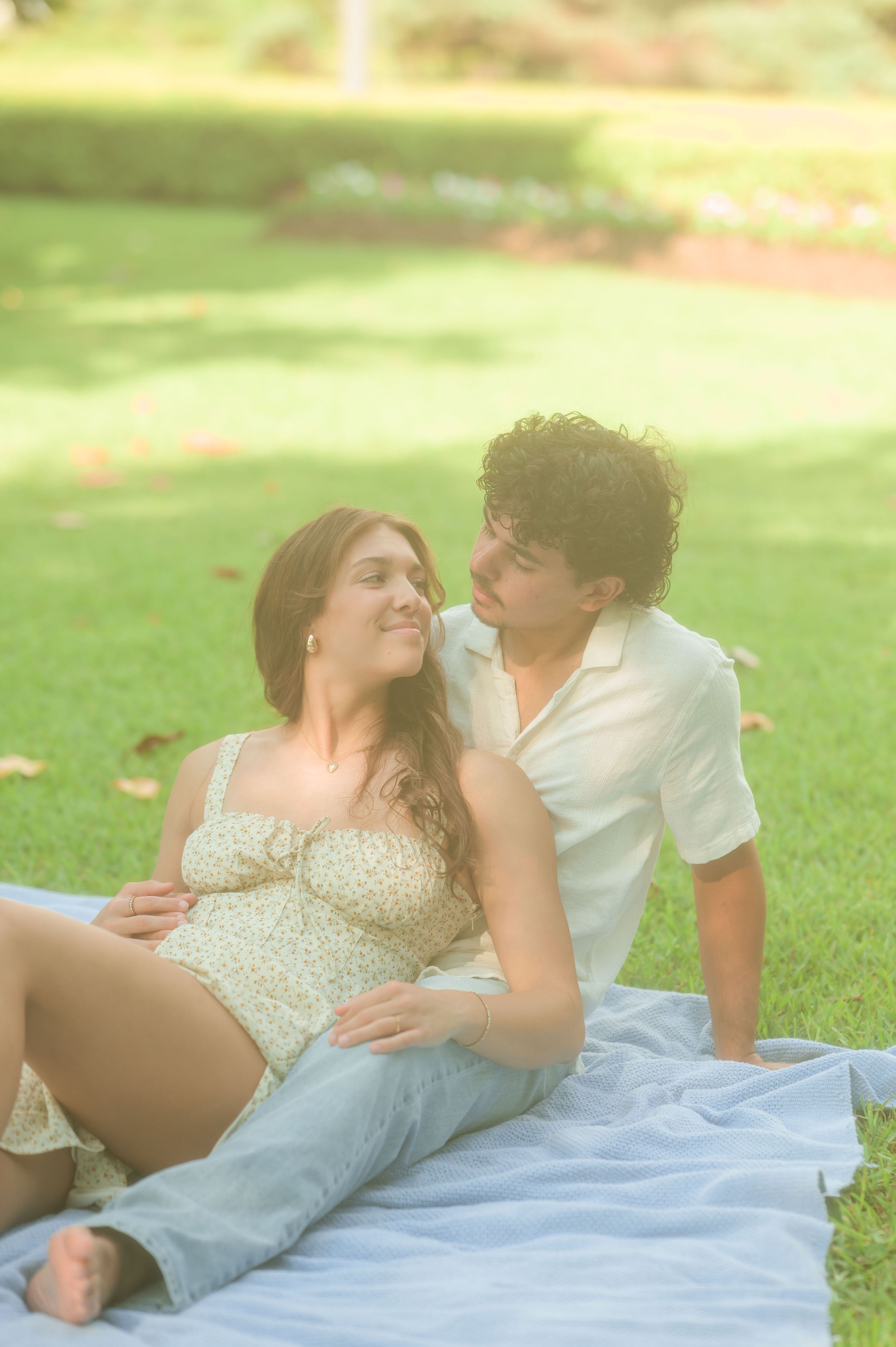 Couple relaxing on blanket in park sharing tender moment.