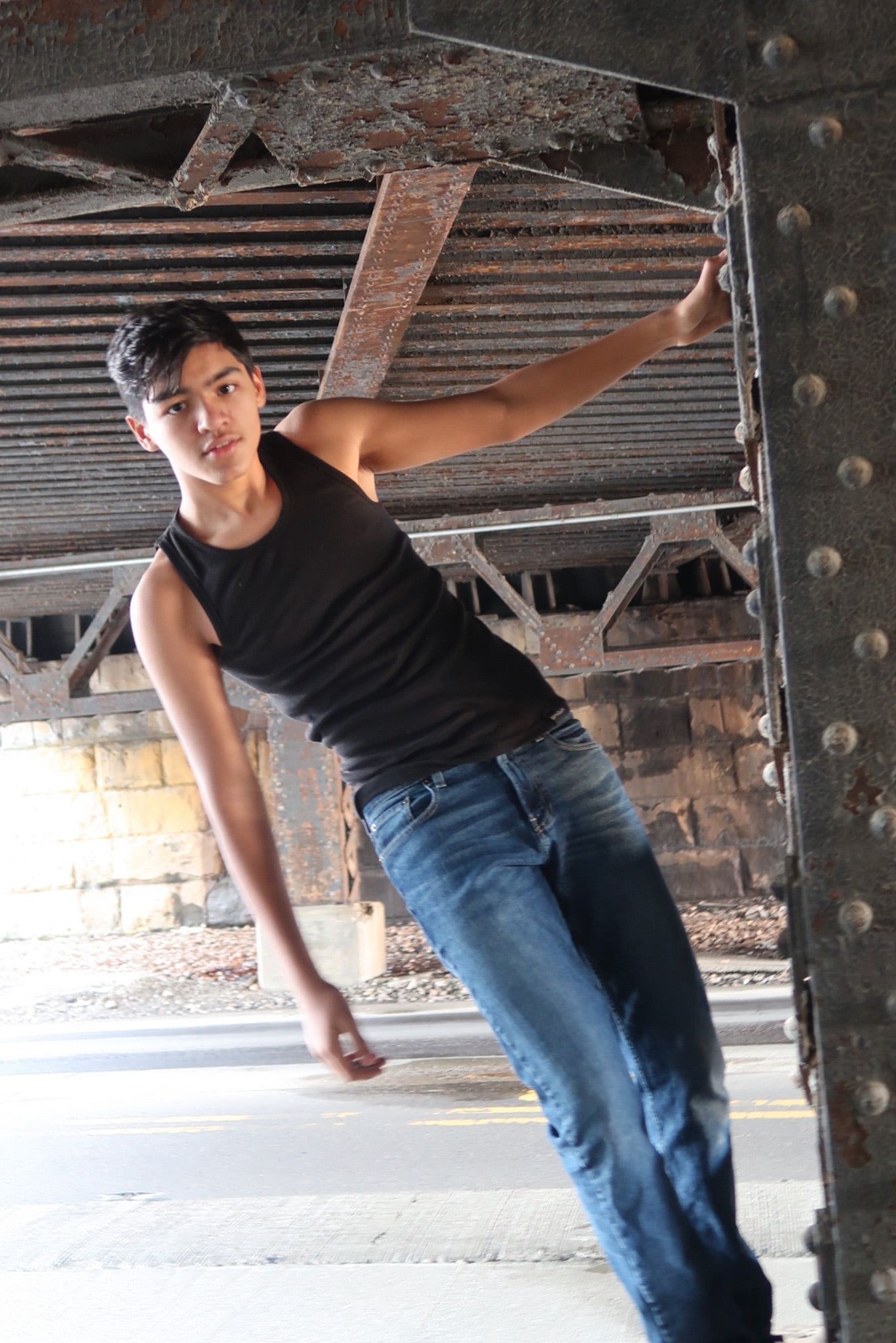 Artistic urban photo featuring casual black tank top and jeans against industrial architecture background.