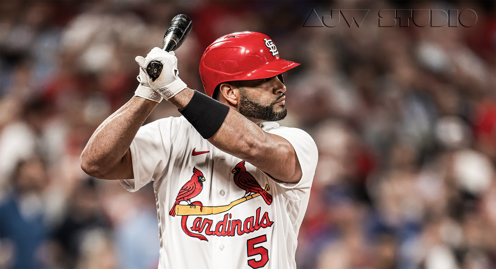 Baseball player in Cardinals uniform takes batting stance at home plate.