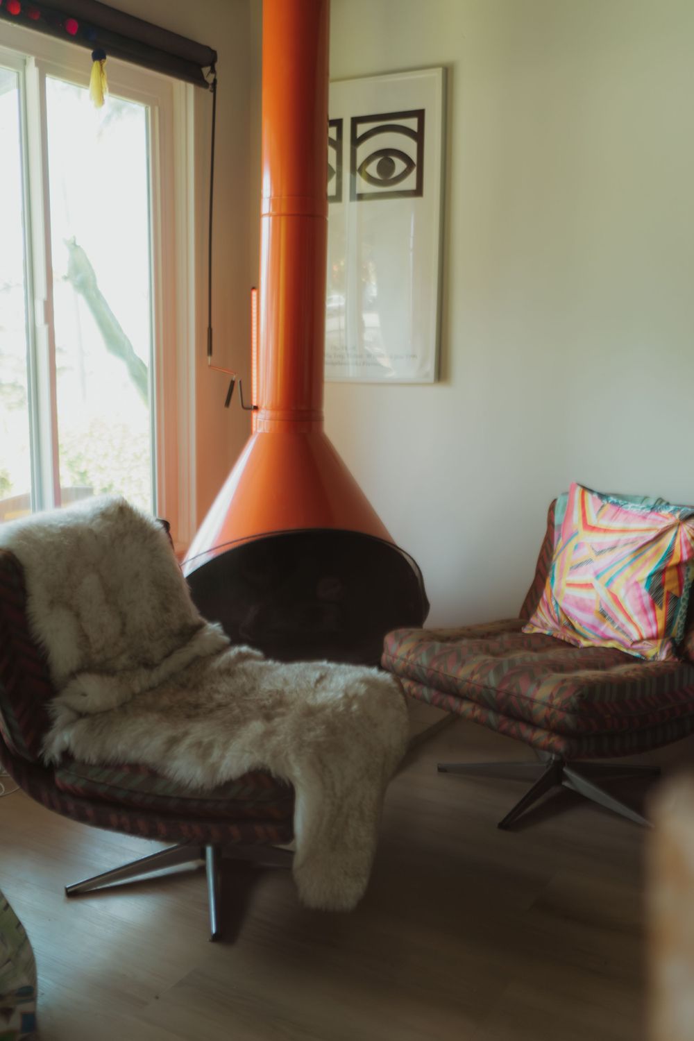 a livingroom with orange fireplace and two chairs