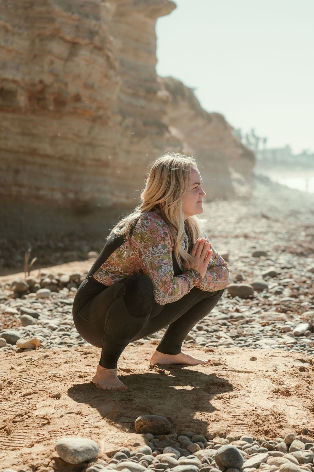 a woman stretching on a rocky shoreline