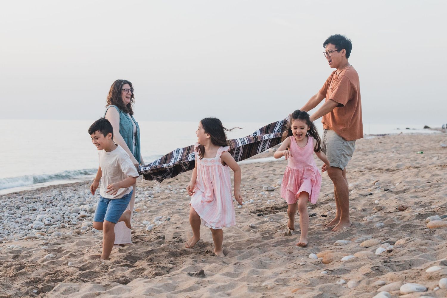 Family walking together hand in hand on a beach at sunset.