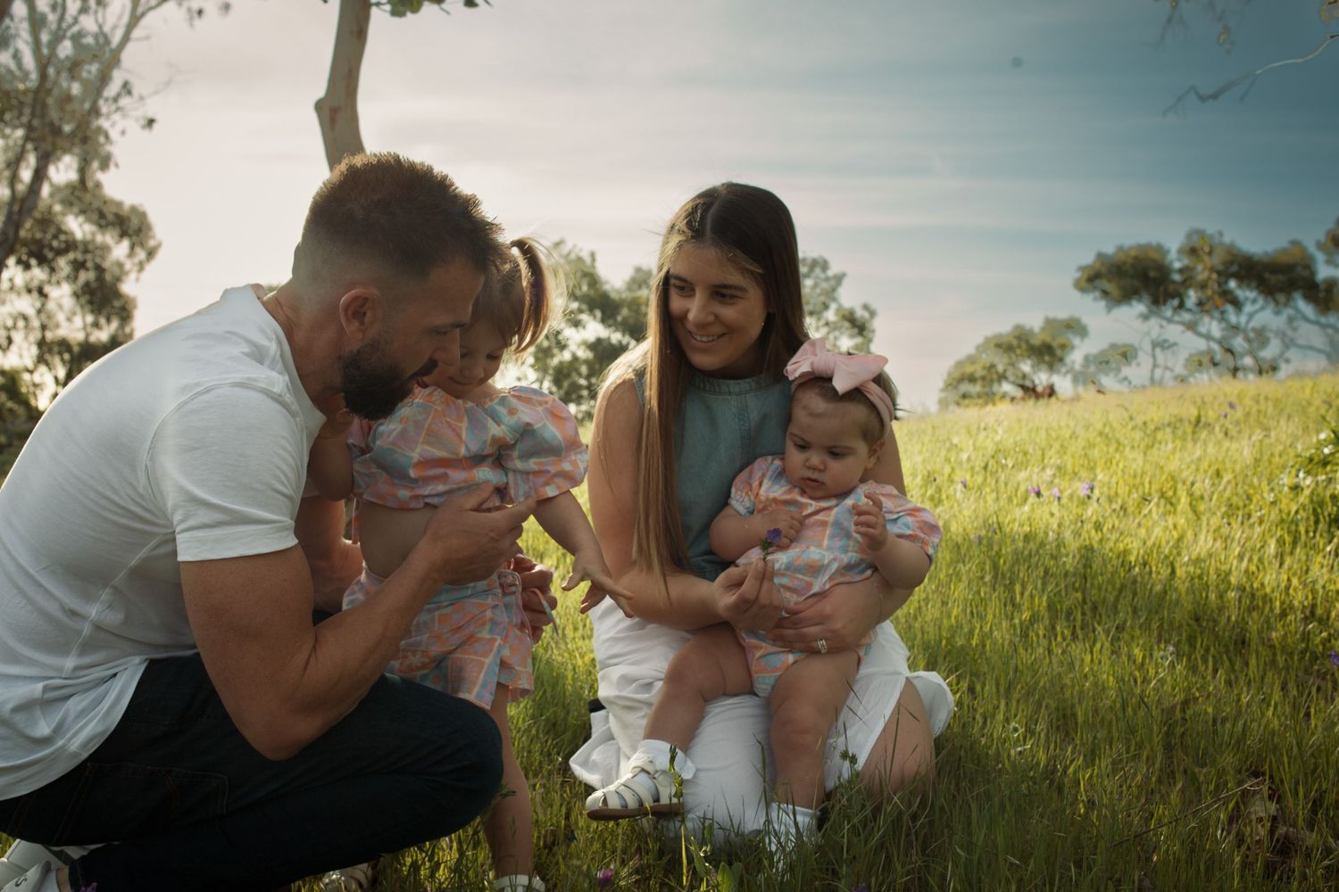 Tender family moment captured in a sunlit meadow.