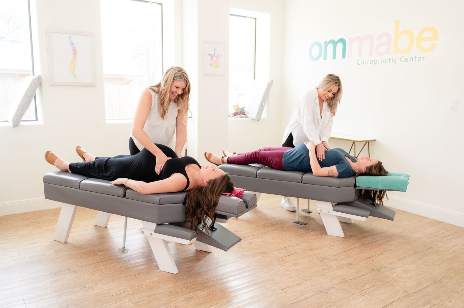 Chiropractors performing spinal adjustments on patients in bright modern clinic.
