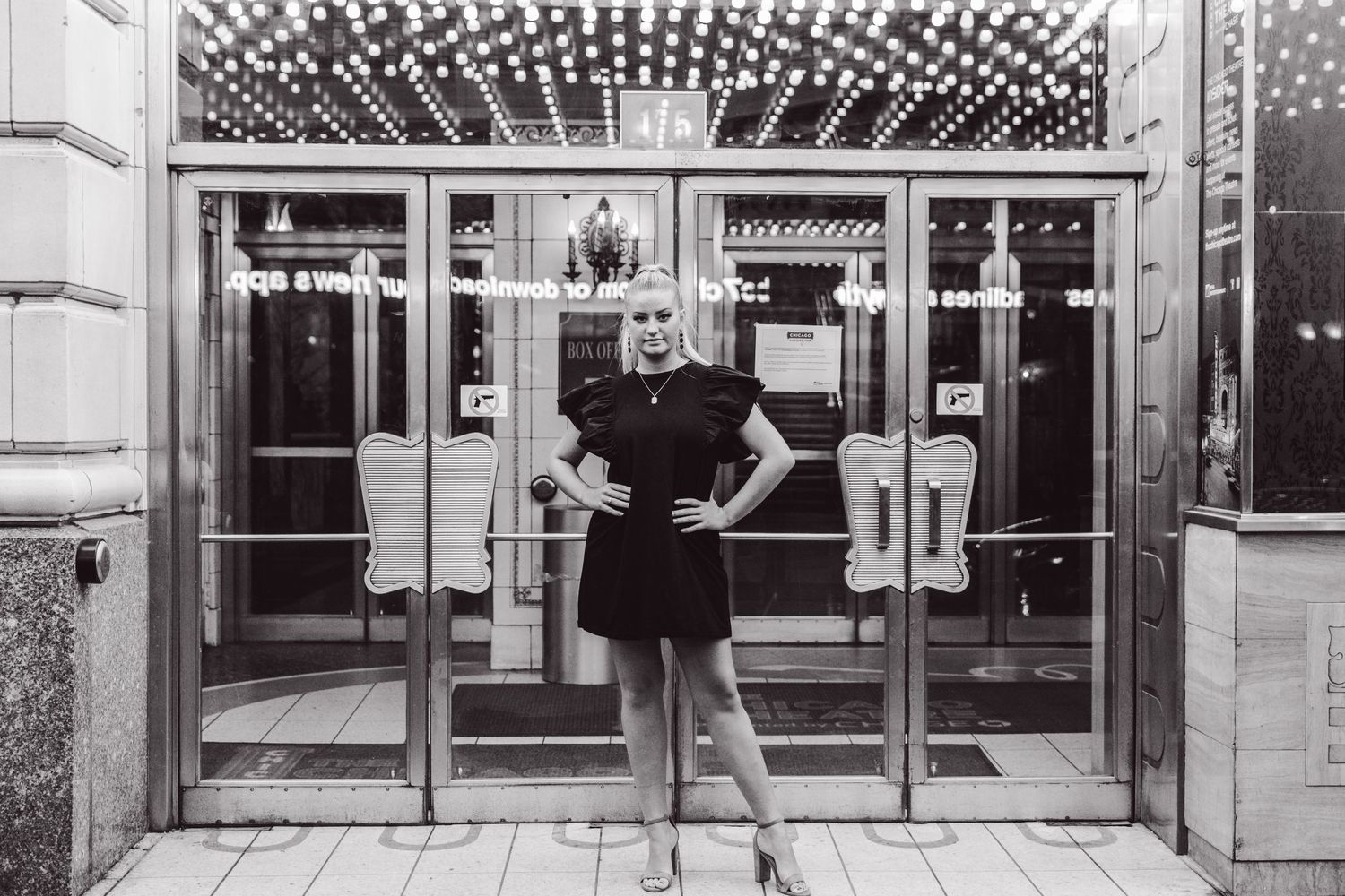A vintage black and white photo showing a striking pose in front of an illuminated storefront.