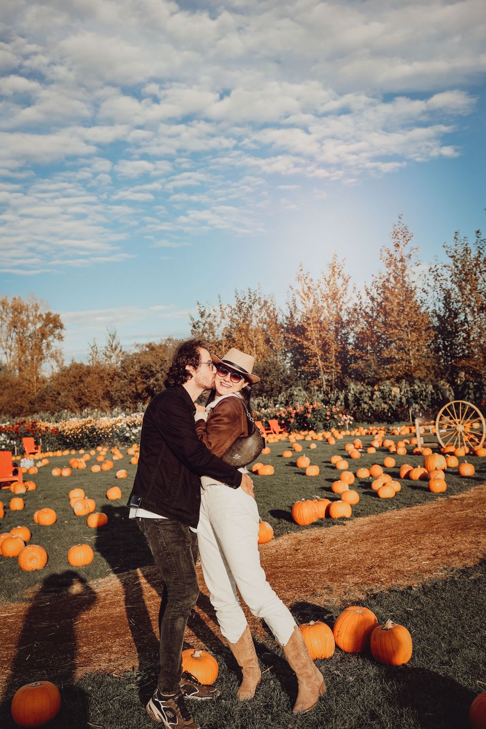 Couple enjoying a romantic moment in pumpkin patch during golden hour.