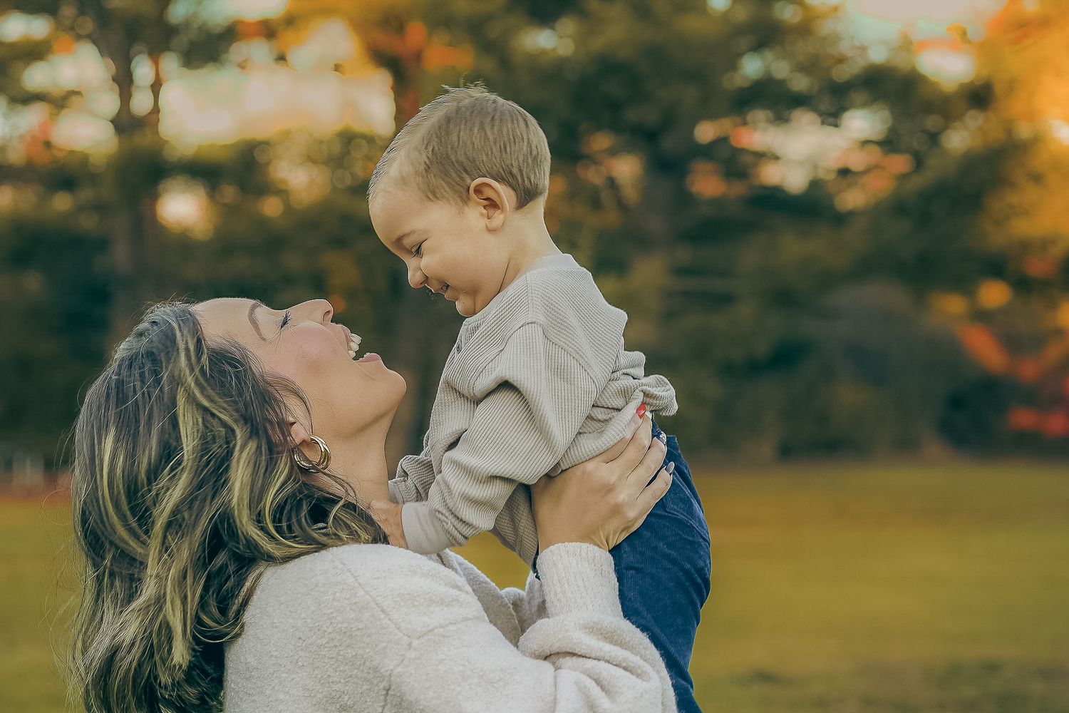 Tender moment captured outdoors with autumn colors in background.
