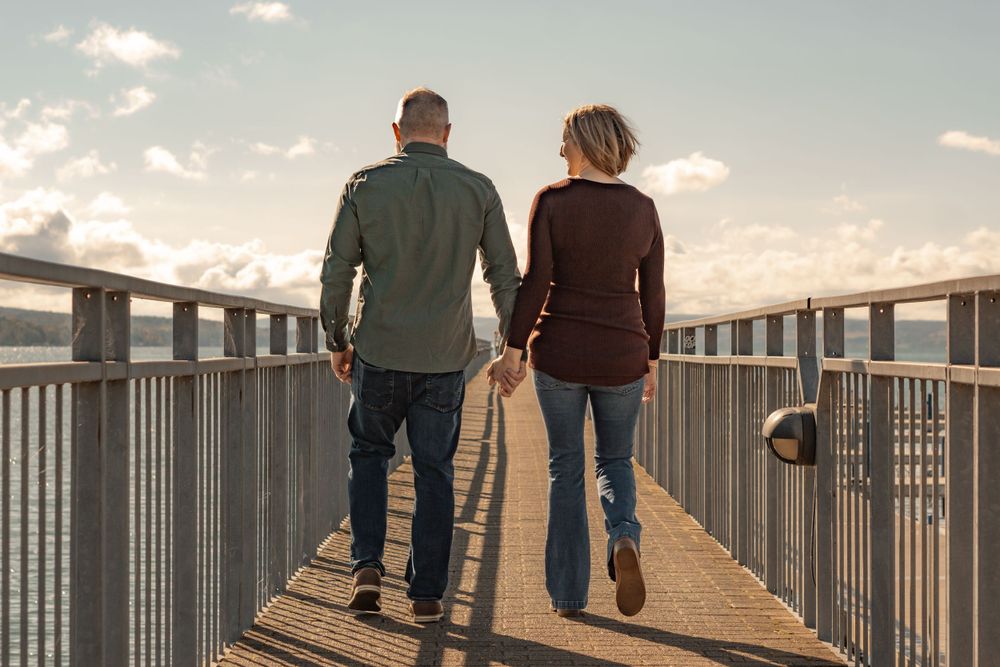 Couple walking together on elevated boardwalk during sunset holding hands.